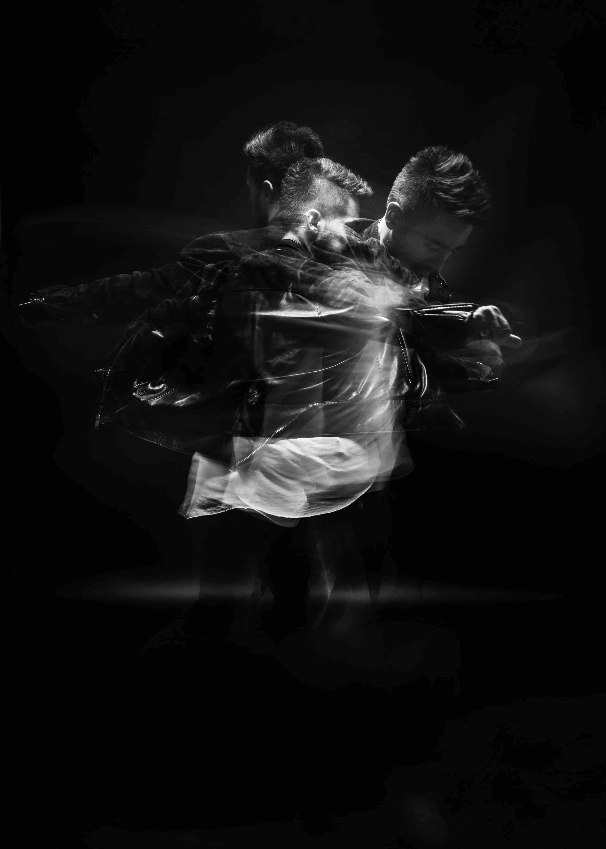 Un homme en mouvement noir et blanc, portant une veste en cuir, avec un effet de flou artistique.